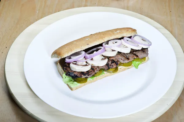 Enkel hem gjorde grundläggande smörgås med tomat skivor, sallad och lök i en batong bulle med saltgurka — Stockfoto