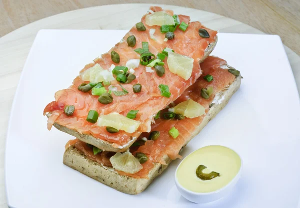 Sándwich básico casero simple con rodajas de salmón rojo, lechuga y cebolla en un pan blanco con pepinillos —  Fotos de Stock