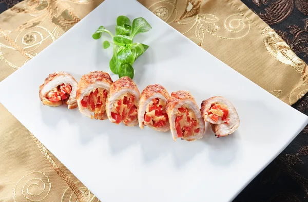 Plate of sliced chicken roll stuffed with tomatoes