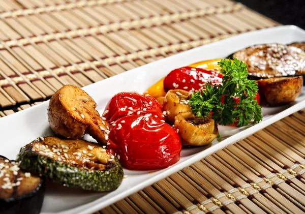 Narrow plate of baked vegetables topped with sesame seeds — Stock Photo, Image