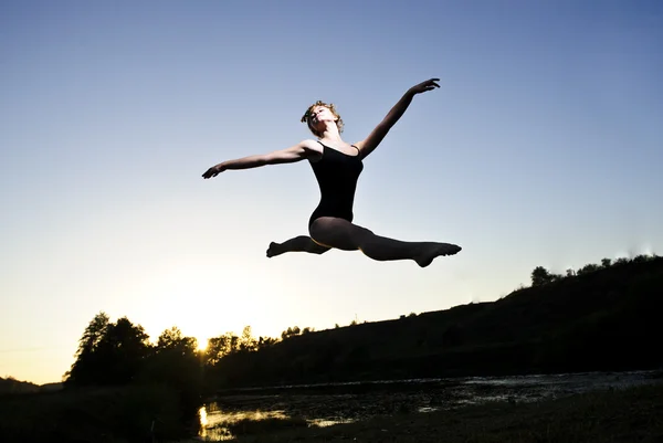 Балетная женщина Ян в тренировочном костюме выступает на открытом воздухе во время захода солнца — стоковое фото