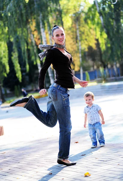 Янг и красивая мама играют на свежем воздухе со своим маленьким сыном — стоковое фото