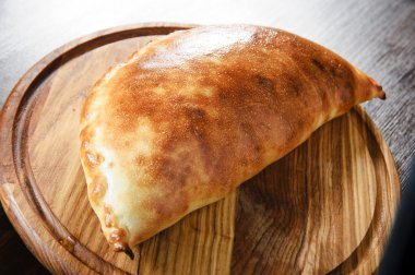 Wooden plate of traditional Italian calzone clipart