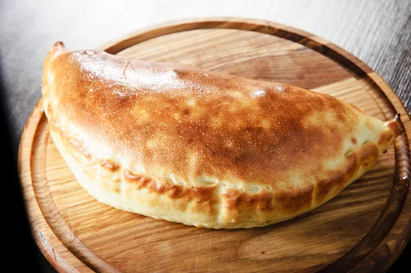 Wooden plate of traditional Italian calzone — Stock Photo, Image