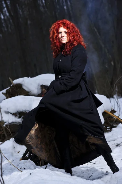 Portrait of red haired beautiful and wild yang woman the hunter in the winter gloomy forest. — Stock Photo, Image