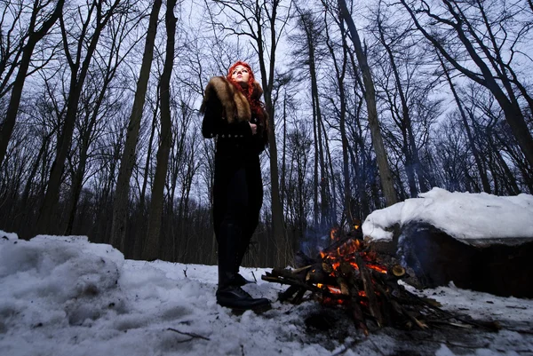Portrait of red haired beautiful and wild yang woman the hunter in the winter gloomy forest. — Stock Photo, Image