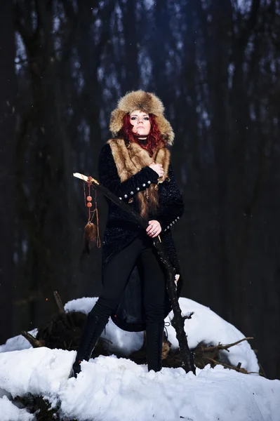 Retrato de la mujer de pelo rojo hermosa y salvaje yang el cazador en el bosque sombrío invierno . — Foto de Stock