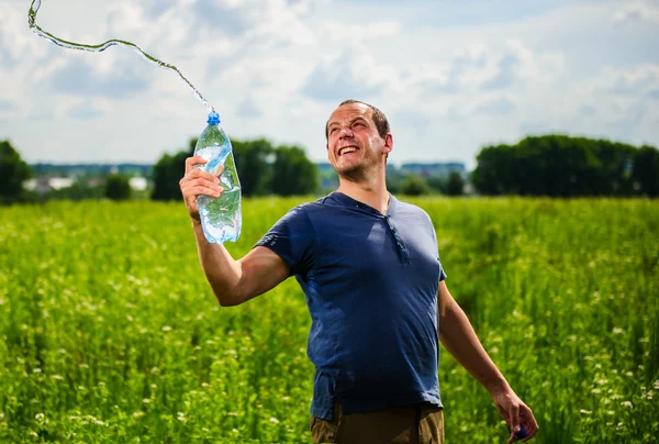 Adult mam plays with water among green field — Stock Photo, Image