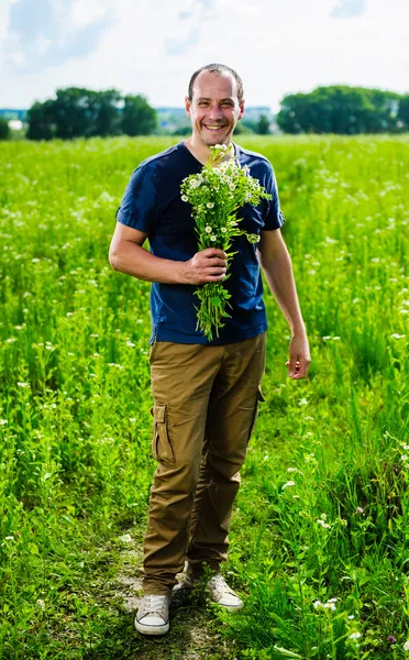 Ritratto di abitante del villaggio con mazzo di fiori in mezzo al campo verde — Foto Stock