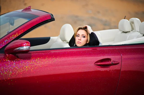 Maneira árabe vestido yang mulher posando em carro vermelho no deserto — Fotografia de Stock
