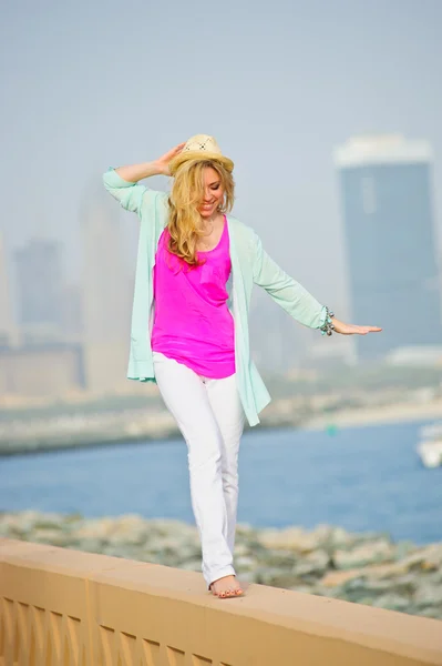 Yang European woman poses in front of sea bay and modern skyscrapers — Stock Photo, Image