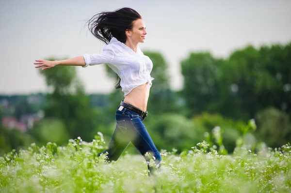 Bella giovane donna europea saltando sul campo verde — Foto Stock