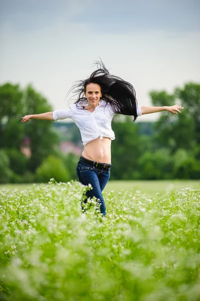 Mujer europea bastante joven saltando en el campo verde — Foto de Stock