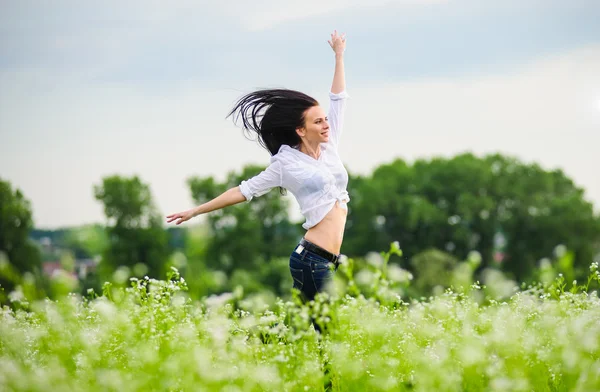 Pretty young European woman jumping on green field — Stock Photo, Image