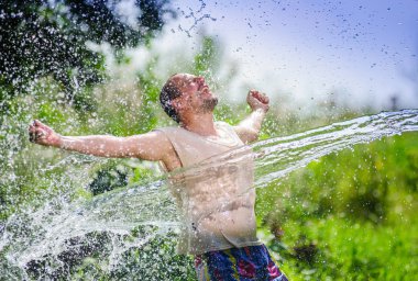 Adult country side man enjoying water sharp flow during summer heat times clipart