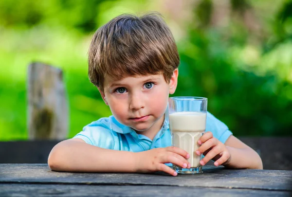 Yang pequeño y lindo chico en la foto con un vaso de leche — Foto de Stock