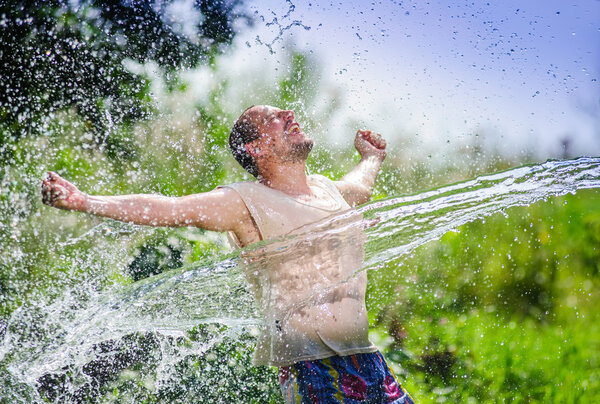 Adult country side man enjoying water sharp flow during summer heat times