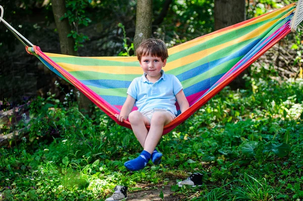 Фото маленького мальчика, сидящего в гамаке на открытом воздухе — стоковое фото