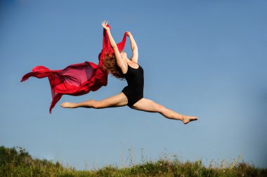 günbatımı gökyüzü ve kırmızı kumaş arka plan önünde poz profesyonel jimnastikçi kadın dansçı