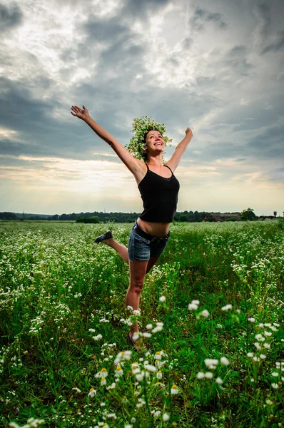 Yang slaviska kvinna i blomma krans poserar bland gröna fält — 图库照片