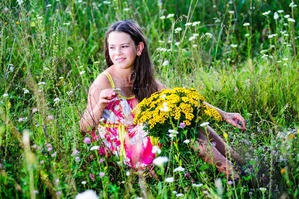 Portret van school meisje onder de bloemen in de zomer — Stockfoto