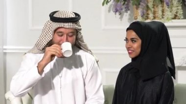 Arap çift evlerinde oturmuş, radyoaktif elbiseler giyiyor ve kahve içiyorlar.