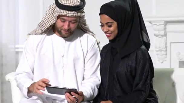 Αραβικό Ζευγάρι Στο Σπίτι Κάθεται Στο Ακτινωτό Φόρεμα Χρησιμοποιώντας Κινητό — Αρχείο Βίντεο