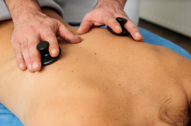 Kaplıca salonundaki masaj masasında sırt ve omuz masajı yapan erkek masörün yakın görüntüsü. Mükemmel ciltli güzel bir kadın rahatlatıcı bir masaj yaptırıyor..