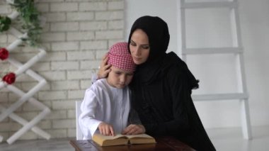mutlu Arapça anne ve oğlu birlikte kanepede oturan ve bir kitap okuma.
