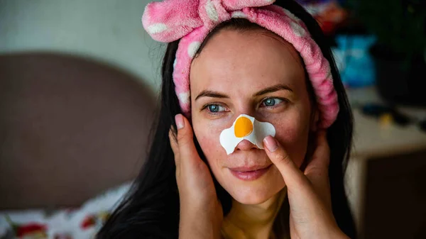 Excited lady posing with white skin stickers on nose and forehead, isolated over interior background