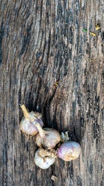 Sarımsak karanfilleri üst üste yığılmış. Ahşap masa arka planında sarımsaklı karanfil grubu