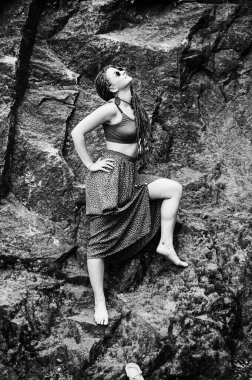 Rastalı güzel bir kız, hippi tarzı giyinmiş, dışarıda poz veriyor..