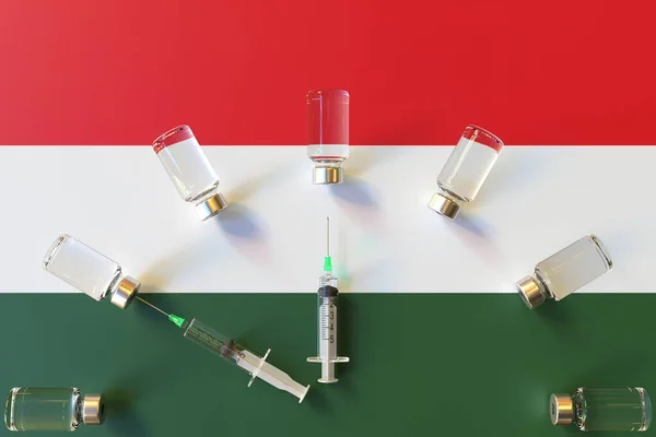 Glazen flacons en spuiten op de vlag van Hongarije. Conceptuele 3D-rendering met betrekking tot vaccinatie — Stockfoto
