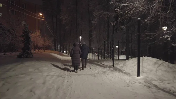 Невідома старша пара практикує скандинавську прогулянку в парку взимку — стокове фото