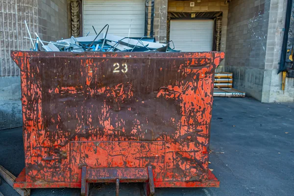 Vuilnisbak vol afvalmetaal achter metalen dakdekkerij — Stockfoto