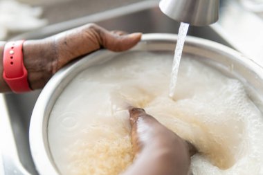 Afro-Amerikalı Nijeryalı kadın yemek pişirmeden önce pirinç yıkıyor