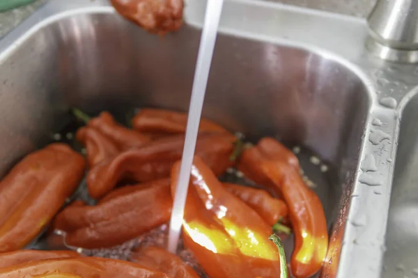 Rode paprika 's gewassen in een wasbak — Stockfoto