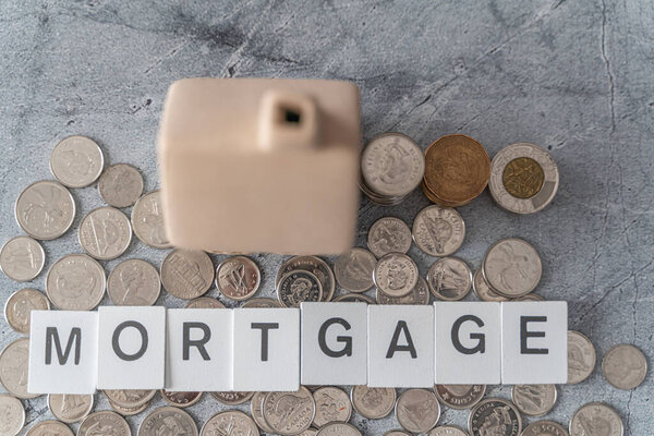 Модельный дом со стопкой монет - Концепция ипотечного финансирования жилья