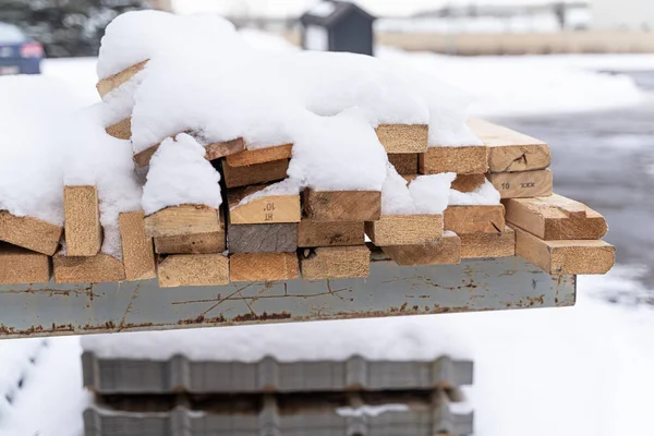 Pilha coberta de neve de madeira serrada em um rack para fazer caixa de transporte — Fotografia de Stock