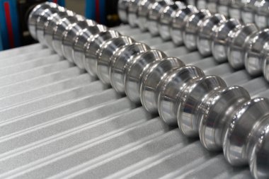 Oluklu metal çatı paneli eski makineden geçiyor.