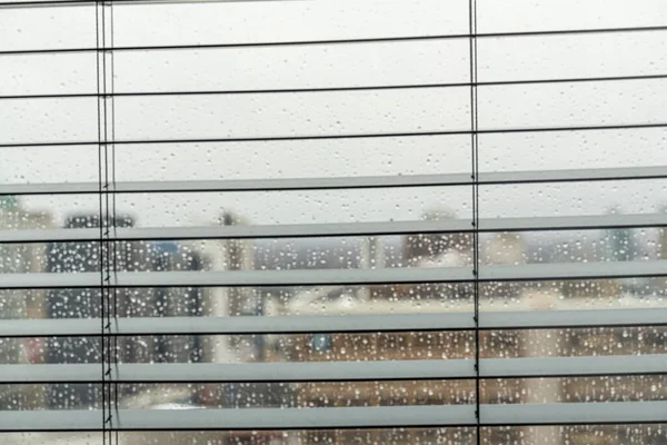 Titta ut genom fönsterpersienner på regnig dag — Stockfoto