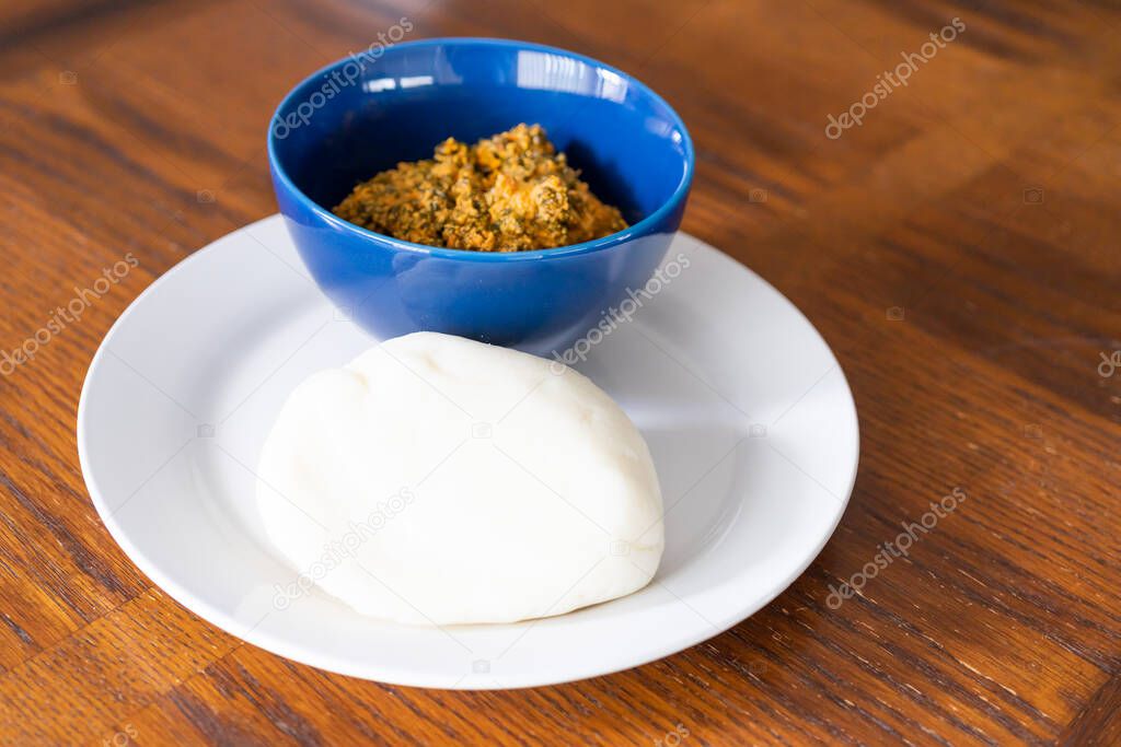 Nigerian Egusi Soup in Blue bowl Served with ponded Yam