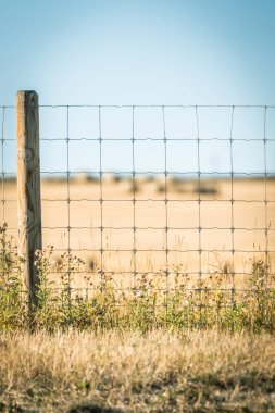 Arkasında tarlalar olan tel örgüler.