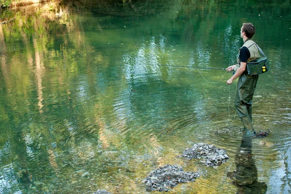 En fiskare som fiskar på en flod — Stockfoto