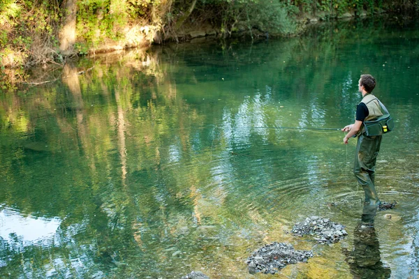 Un pescatore che pesca su un fiume — Foto Stock