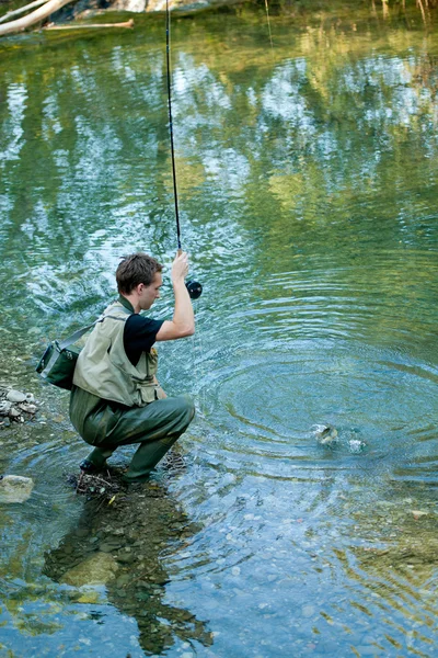 Un pescatore che pesca su un fiume — Foto Stock