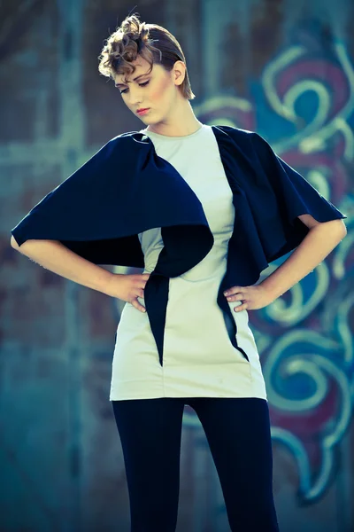 Bella modella di moda in indumento grigio e nero in posa vicino al muro di ferro — Foto Stock