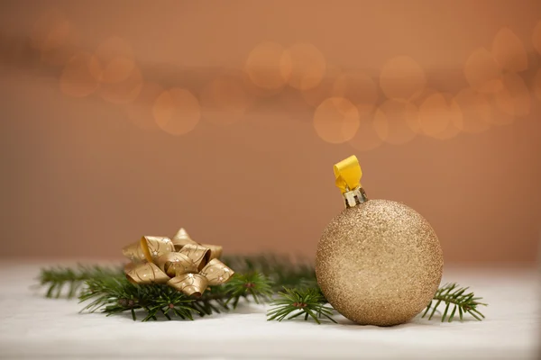 Weihnachtsschmuck - goldene Christbaumkugel mit glänzendem Band im Hintergrund — Stockfoto