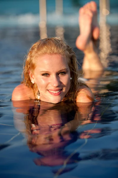 Attractive blonde girl in bikini swimwear in swimming pool on late summer afternoon — Stock Photo, Image