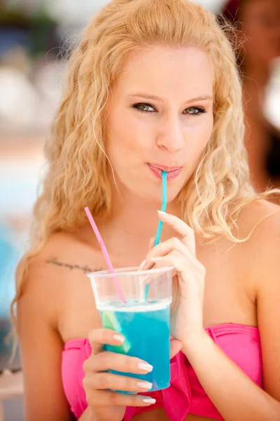 Jolie fille blonde boit cocktail bleu dans l'ombre un après-midi d'été chaud — Photo